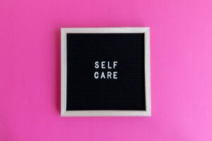 A motivation message 'Self Care' displayed on a letter board against a pink backdrop.